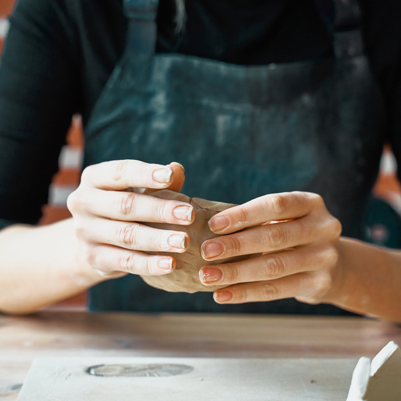 Person holding a piece of clay in a pottery setting