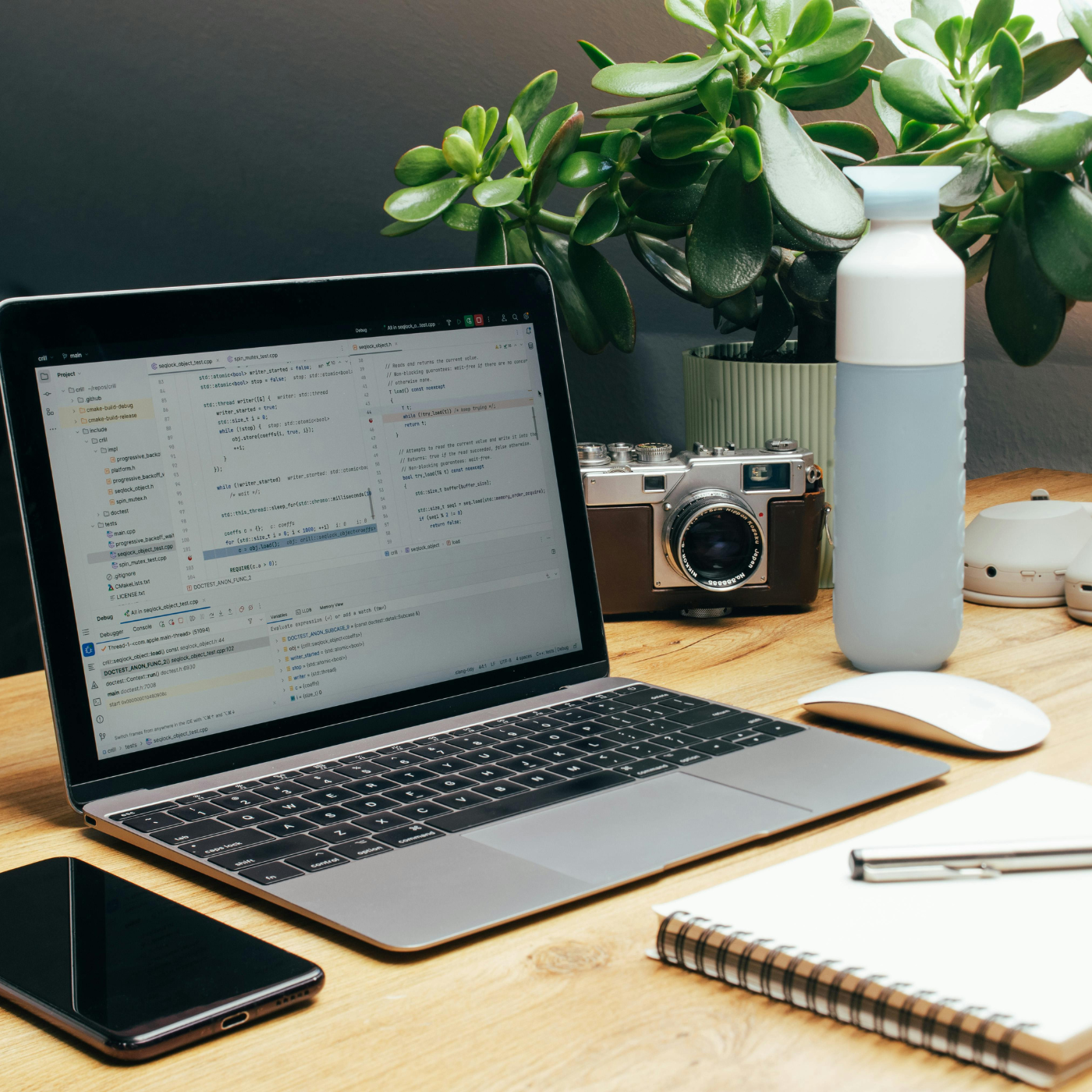 Laptop on a desk with a smartphone, notebook, and water bottle.